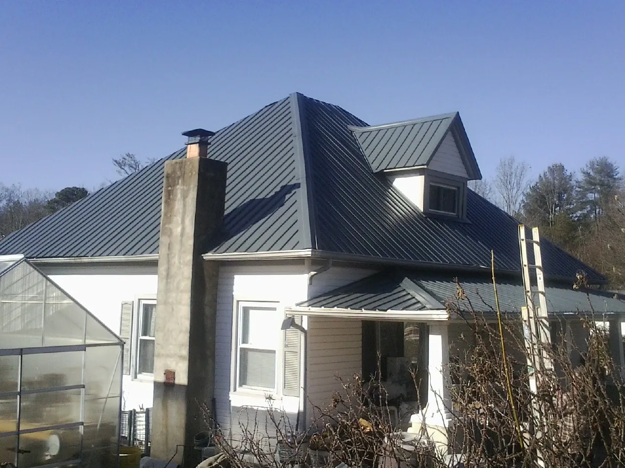Dark blue standing seam metal roof on a white farmhouse with dormer — Slate & Tile Roof Repair by Roofing Brothers in Rutherfordton