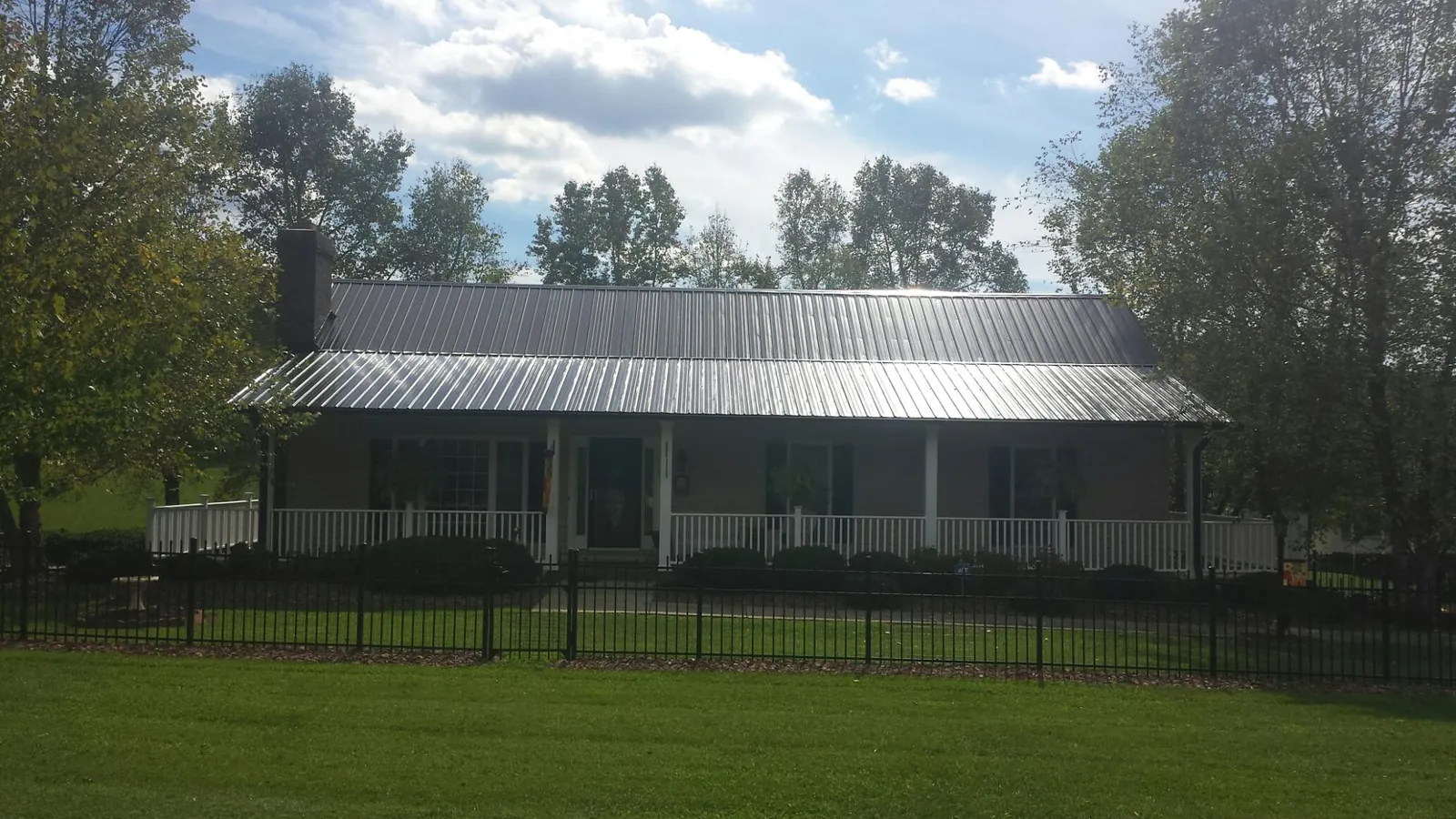 Gray metal roof on a brick ranch with a full width front porch — Gutter Guard Installation work by our crew in Rutherfordton