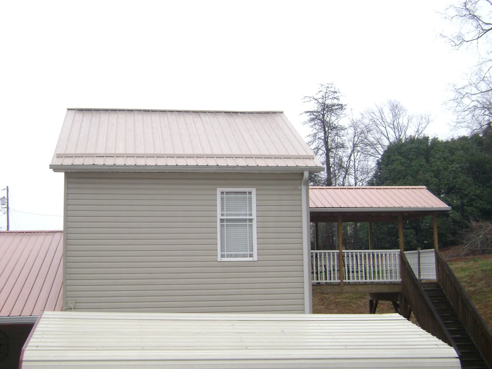 Tan metal roofs on a two story addition and attached porch, from a Roof Replacement job in Rutherfordton