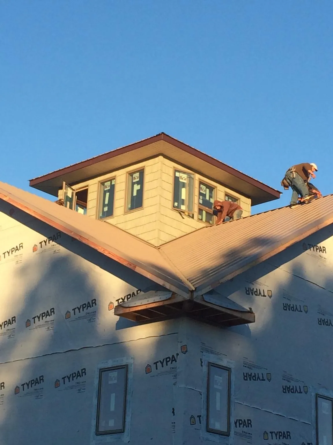 Roofers working around a rooftop cupola on a new metal roof at sunset — Roof Waterproofing in Rutherfordton by Roofing Brothers